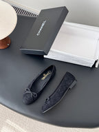Pair of women's dark ballet flats with lace-up bows, rounded toe profile