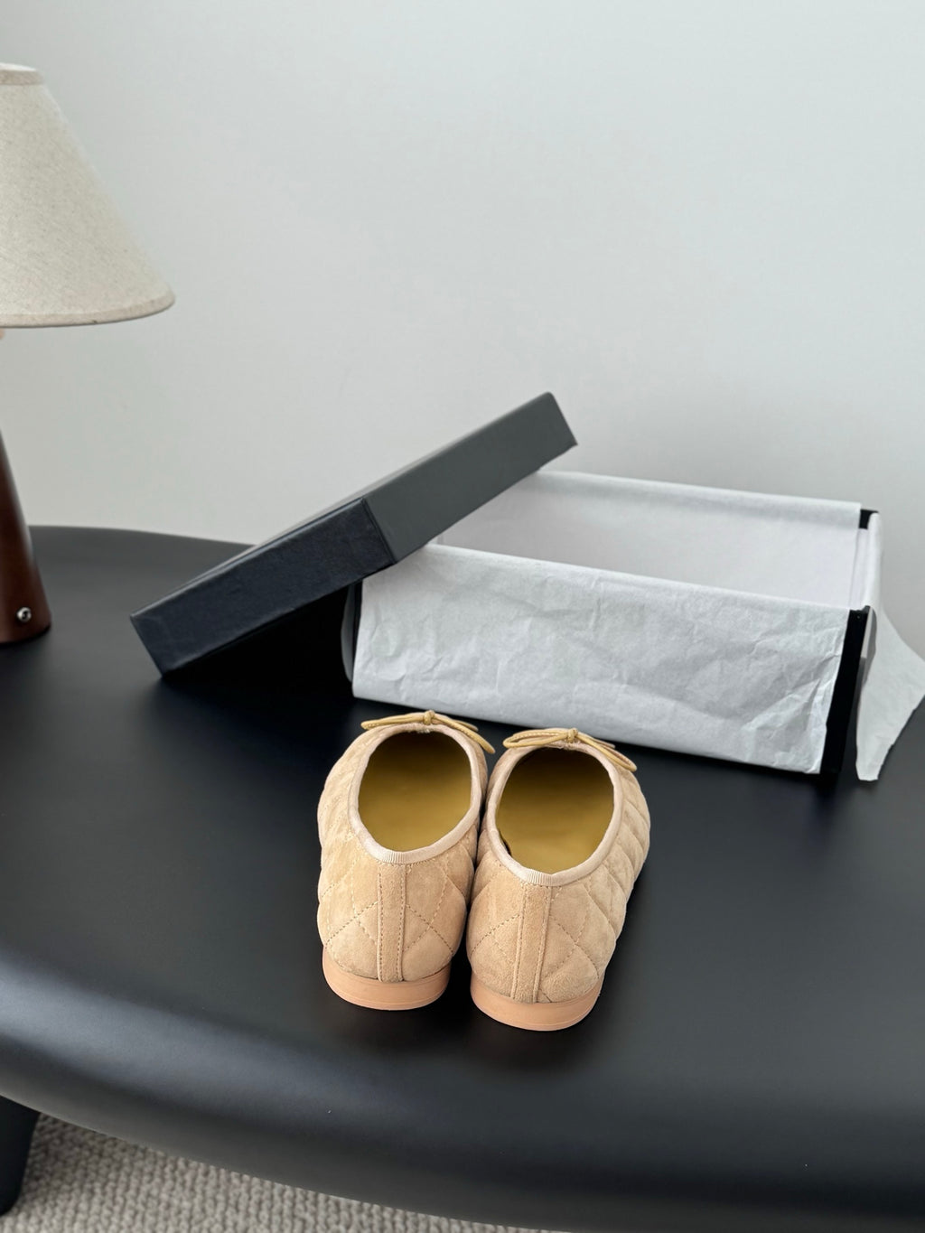 Beige quilted ballet flats viewed from behind, round toe and bow detail