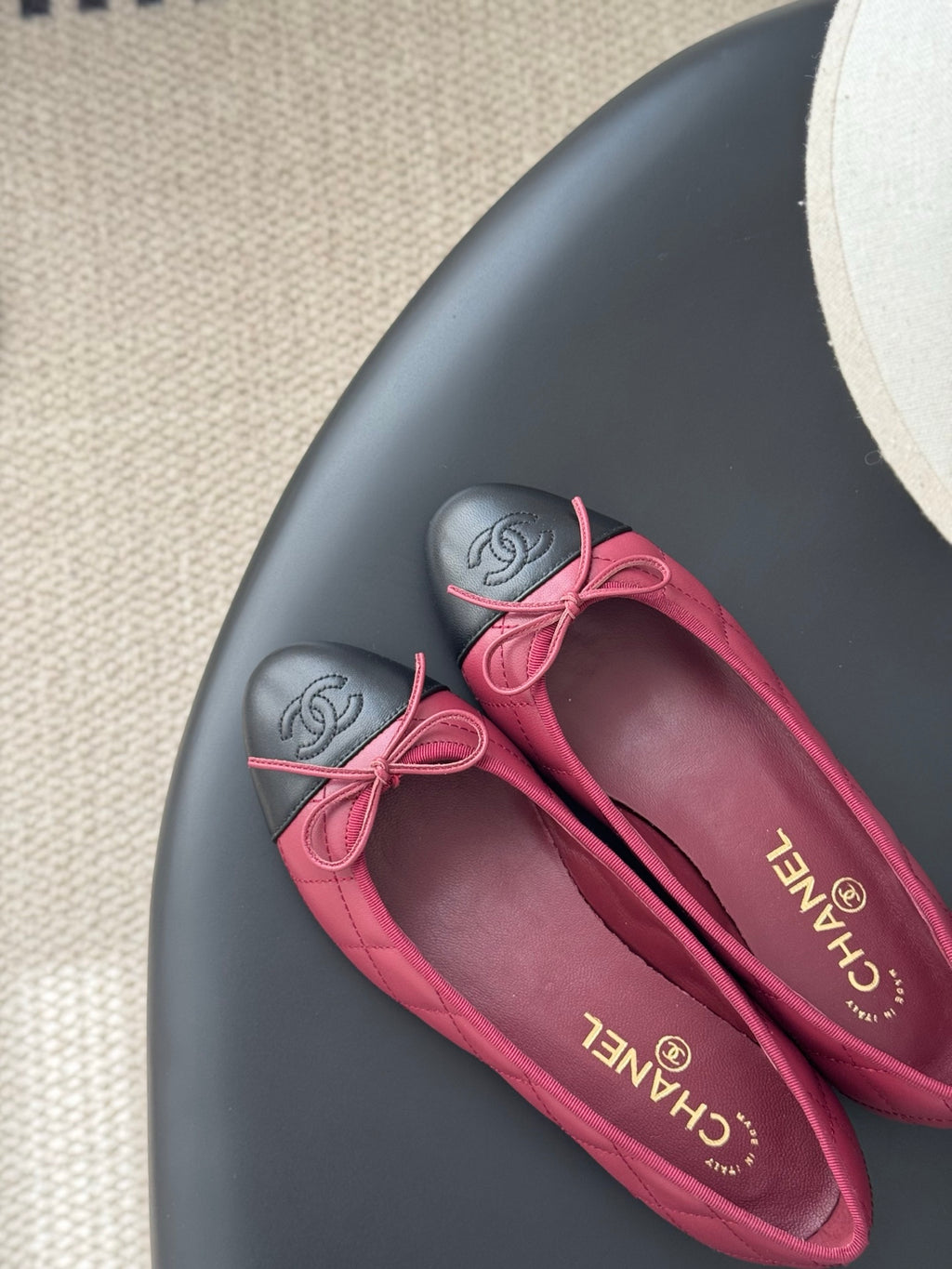 Pink quilted ballet flats with bow laces and black toe cap, close-up