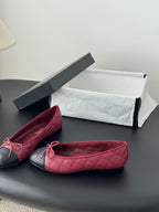 Pair of quilted ballet flats with pink uppers and black toe caps, tied bows