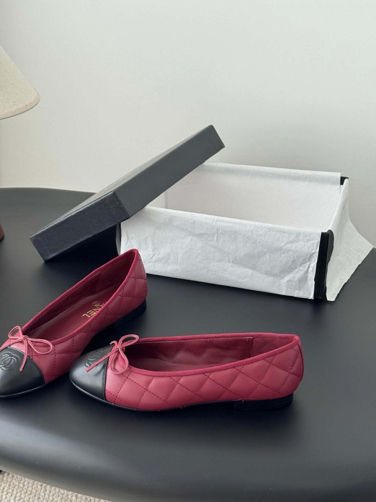 Pair of quilted ballet flats with pink uppers and black toe caps, tied bows