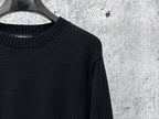 Black long-sleeve knit sweater with ribbed neckline and subtle side seam.