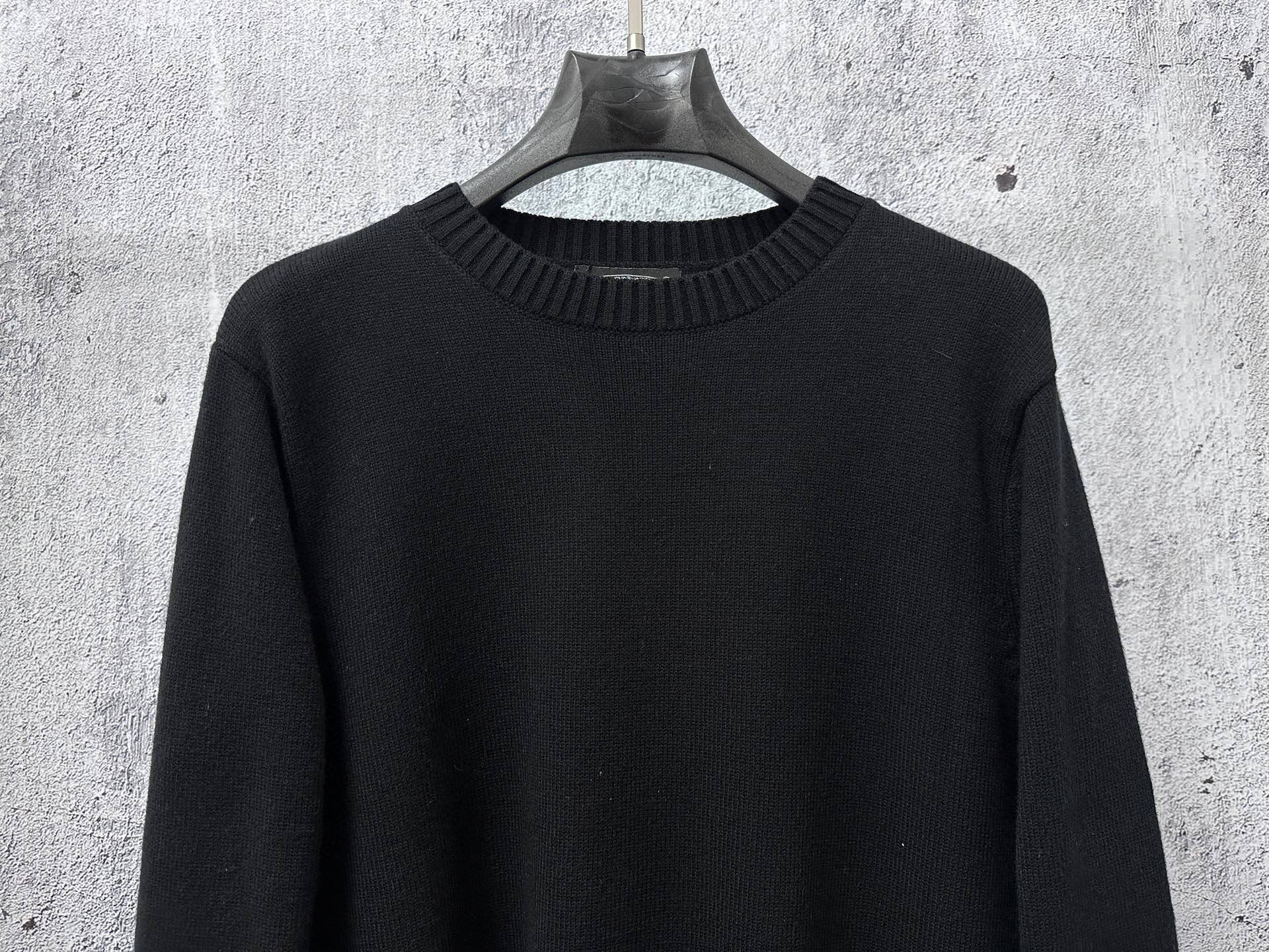 Black long-sleeve knit sweater with ribbed mock neck collar.