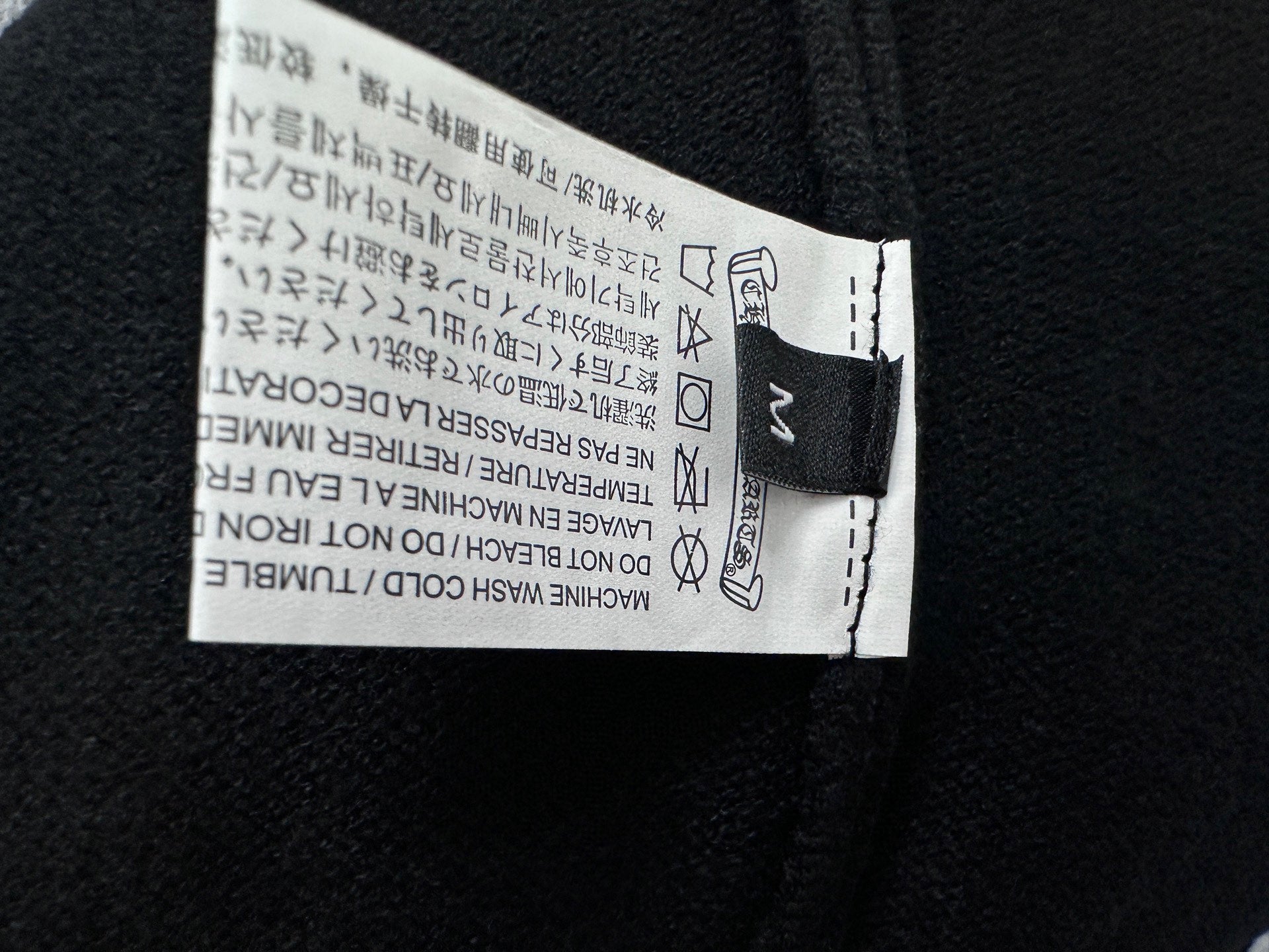 Black clothing tag label inside the neckline with care instructions.