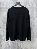 Black long-sleeve knit sweater with ribbed crew neck and stitched back detail.