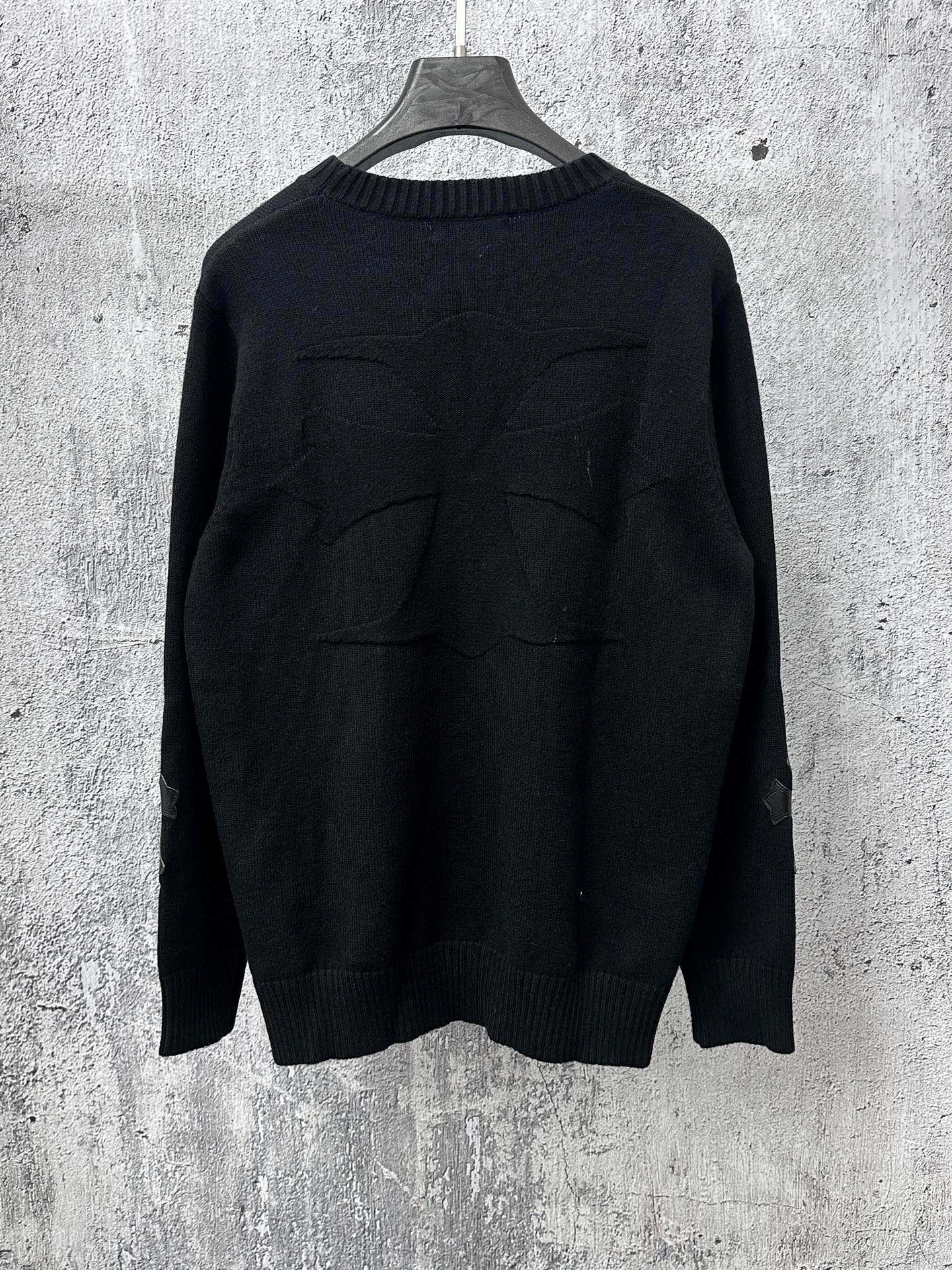 Black long-sleeve knit sweater with ribbed crew neck and stitched back detail.