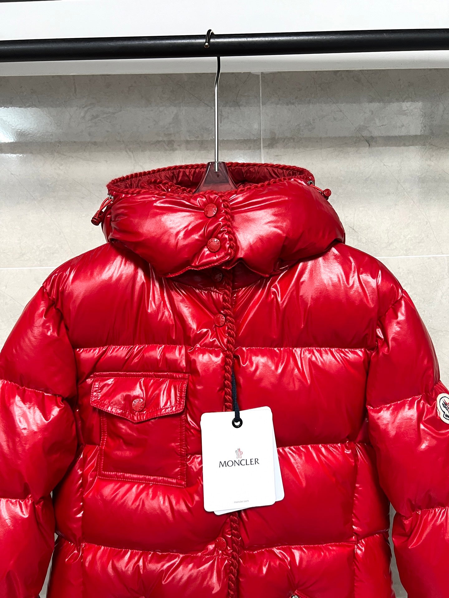 Moncler long red puffer jacket close-up on hood, glossy quilting and front button placket