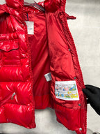 Moncler long red puffer jacket side close-up with zipper pockets and brand tags