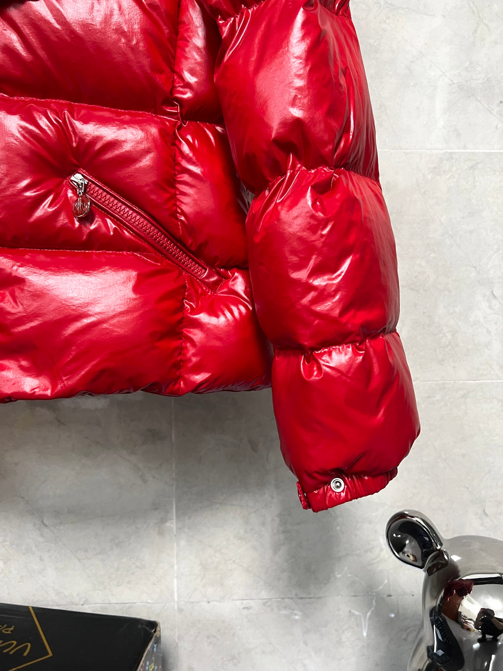 Moncler long red puffer jacket sleeve close-up with zipper pocket and glossy quilting
