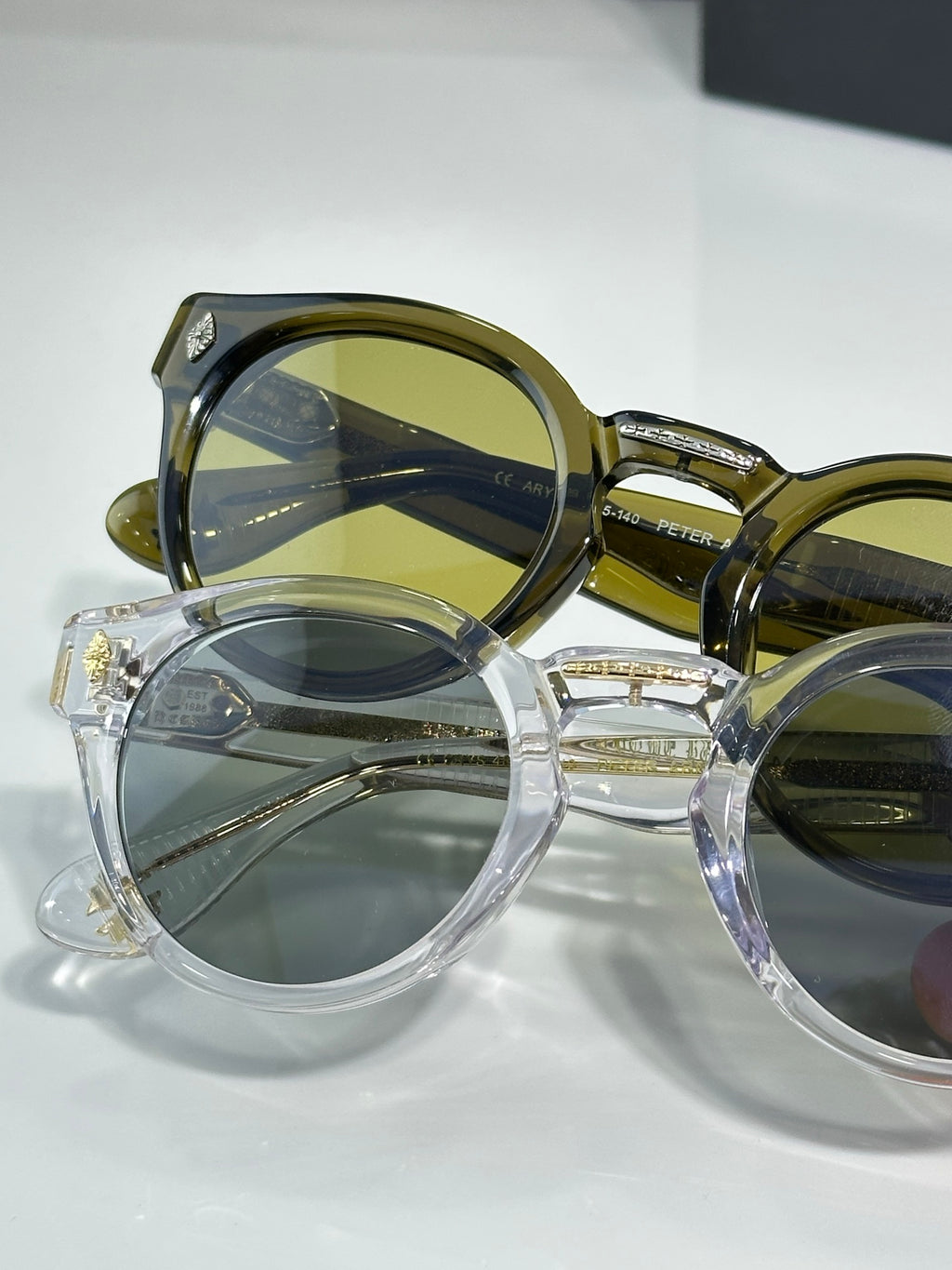 Overlapping chrome glasses with round frames; gold and clear styles with green lenses