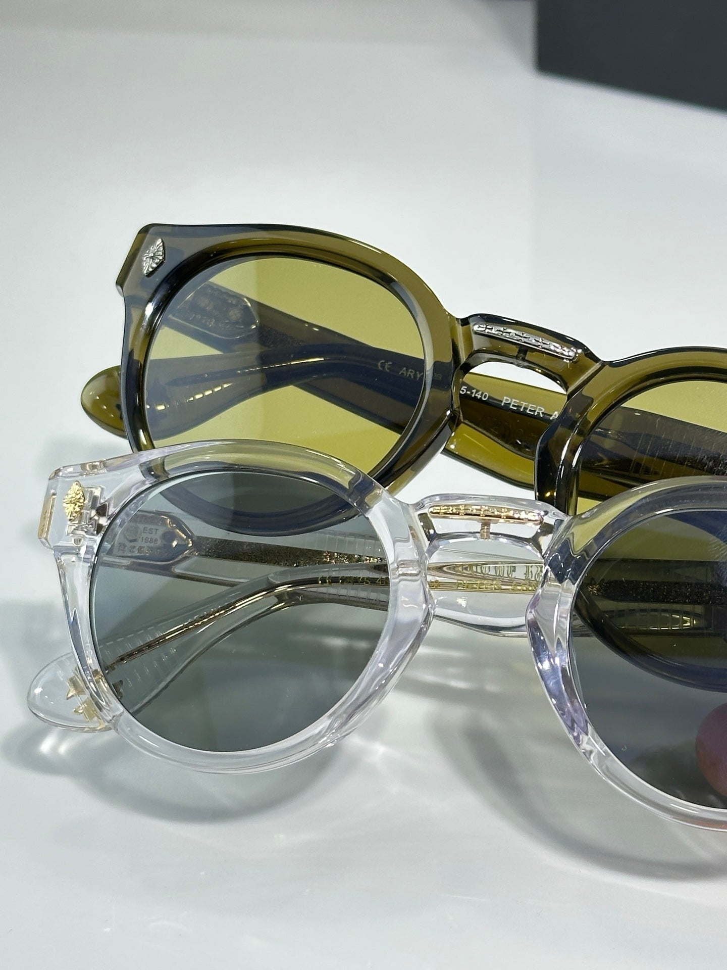 Overlapping chrome glasses with round frames; gold and clear styles with green lenses