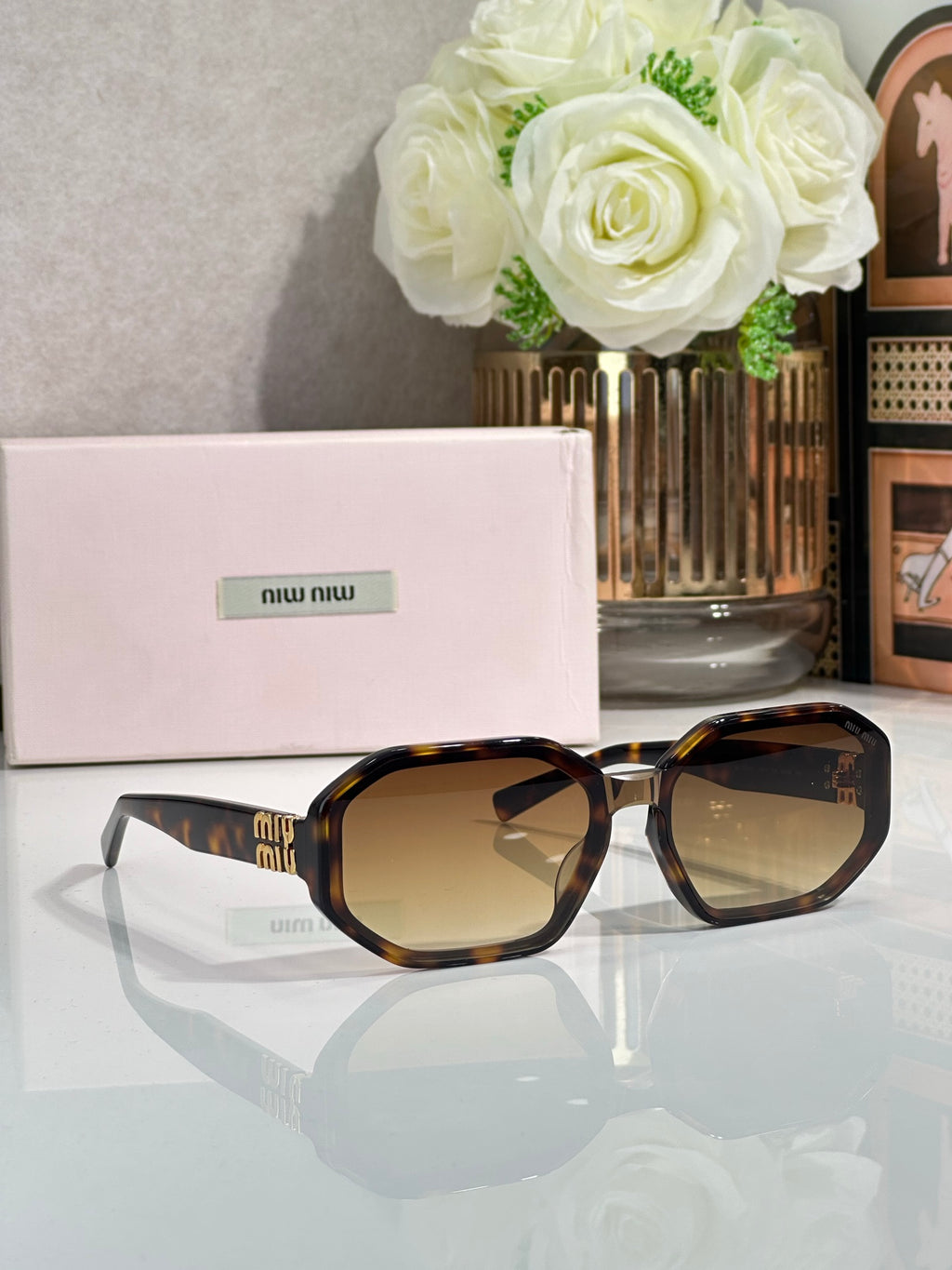 Oversized square sunglasses with tortoise frame and amber-tinted lenses, Miu Miu logo.
