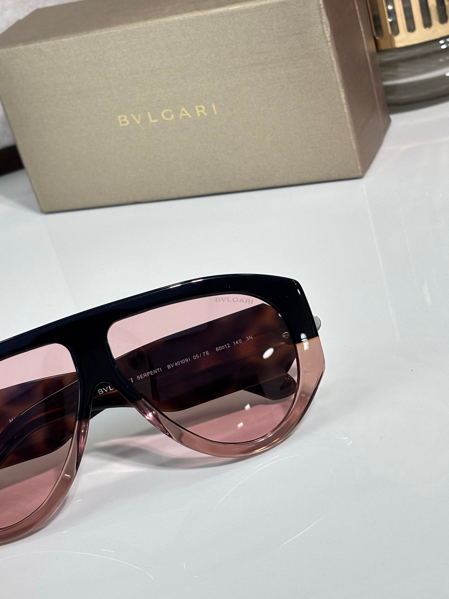 Pink tinted cat-eye sunglasses with dark frame and gold logo detail
