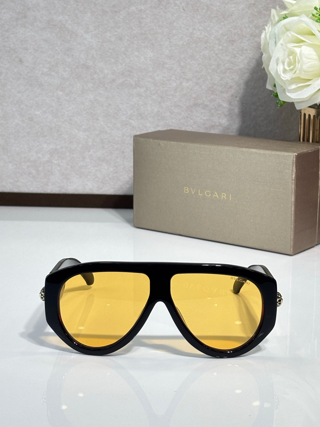 Black cat-eye sunglasses with yellow lenses and gold logo detail