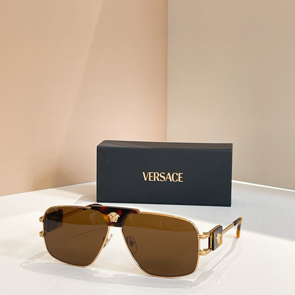 Versace sunglasses with amber-brown lenses, gold frame, and decorative center emblem