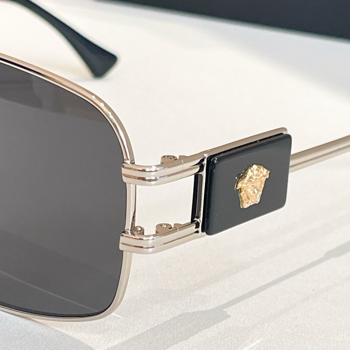 Versace sunglasses temple hinge with gold emblem on a black frame insert