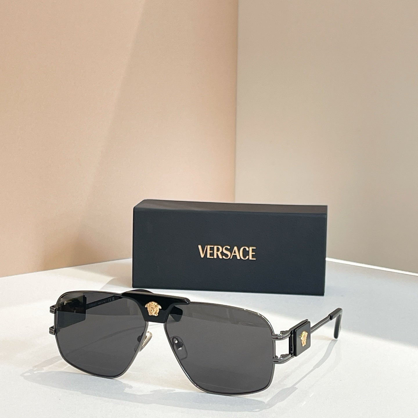 Versace sunglasses with black lenses, silver frame, and gold logo at the bridge