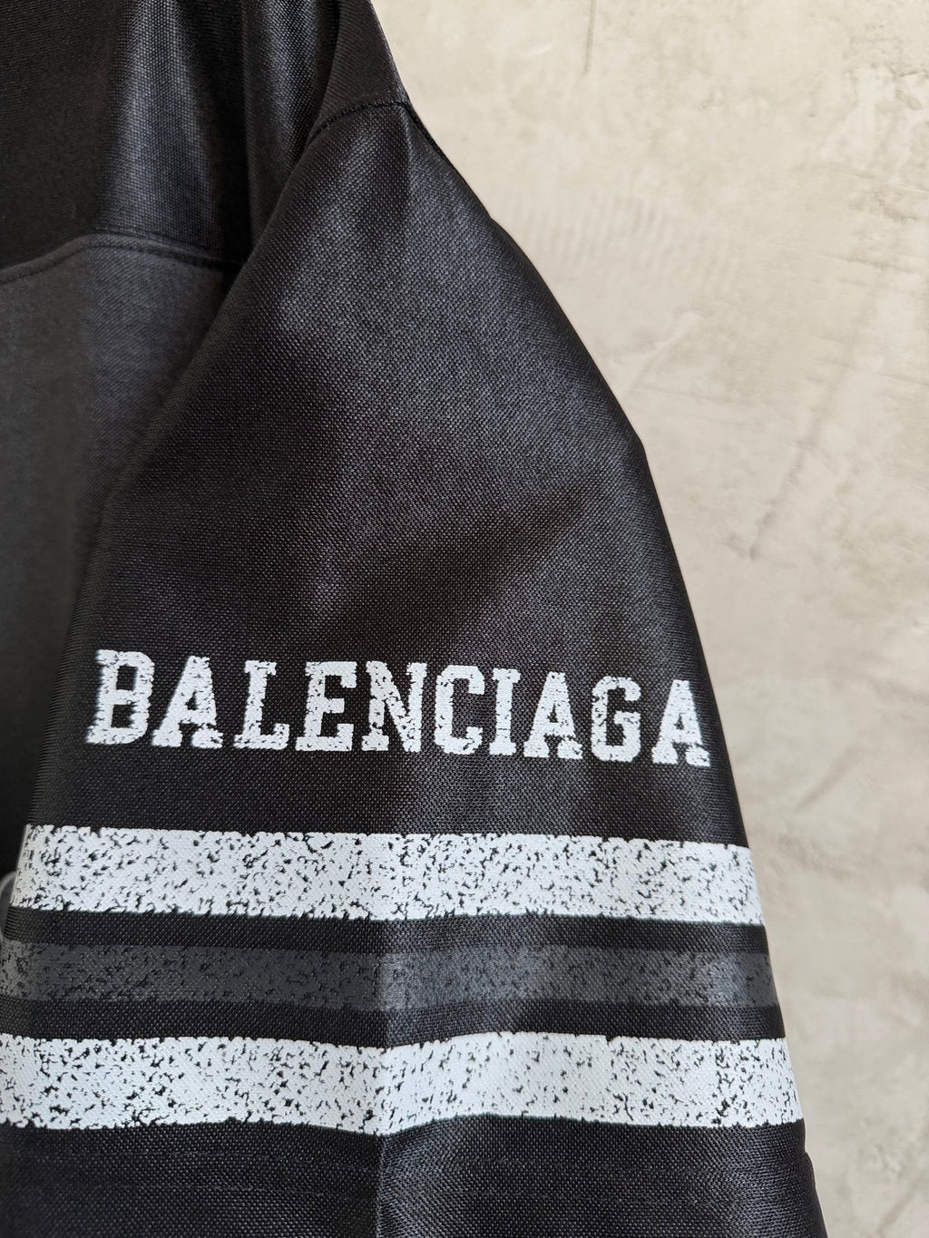 Black Balenciaga polo shirt sleeve with bold 'BALENCIAGA' text and striped band