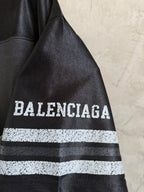 Black Balenciaga polo shirt sleeve with bold 'BALENCIAGA' text and striped band