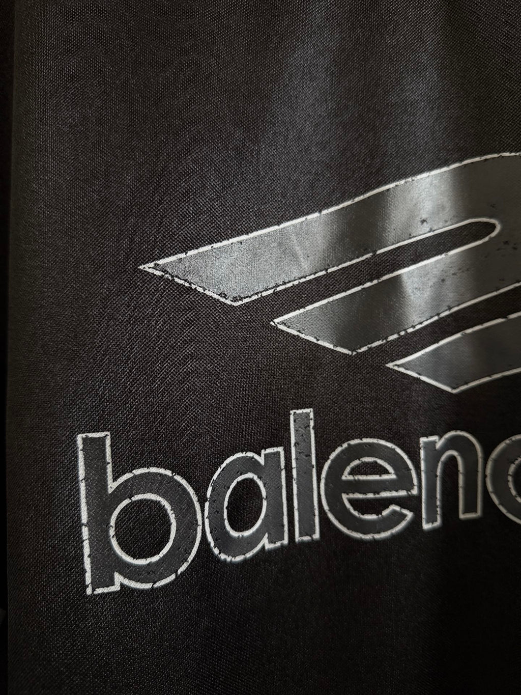 Black Balenciaga polo shirt with graphic lines and partial 'balenciaga' text
