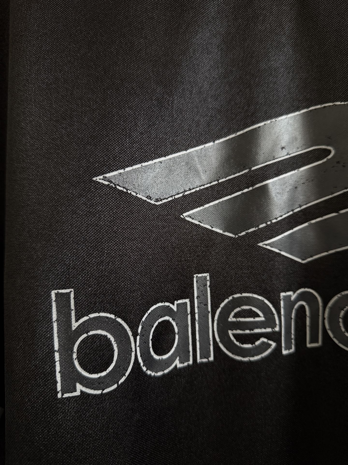 Black Balenciaga polo shirt with graphic lines and partial 'balenciaga' text