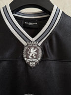 Black polo shirt with striped collar and Balenciaga crest patch at the chest