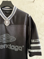 Black Balenciaga polo shirt with embroidered crest, striped sleeve trim, and logos