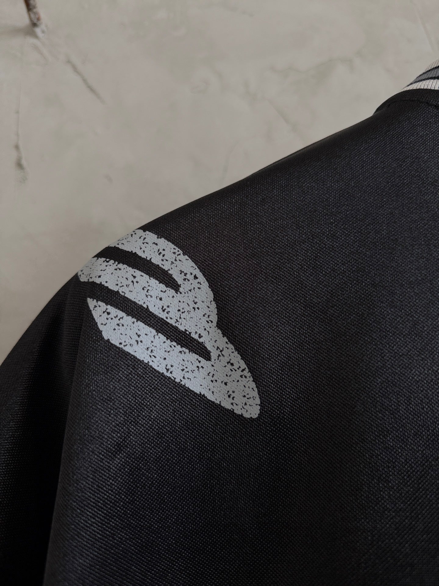 Balenciaga black polo sleeve close-up with white abstract logo graphic