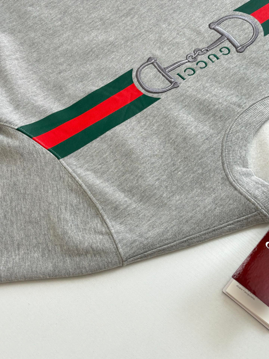 Light gray sweatshirt with green and red stripe graphic on sleeve and cuff