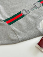 Light gray sweatshirt with green and red stripe graphic on sleeve and cuff