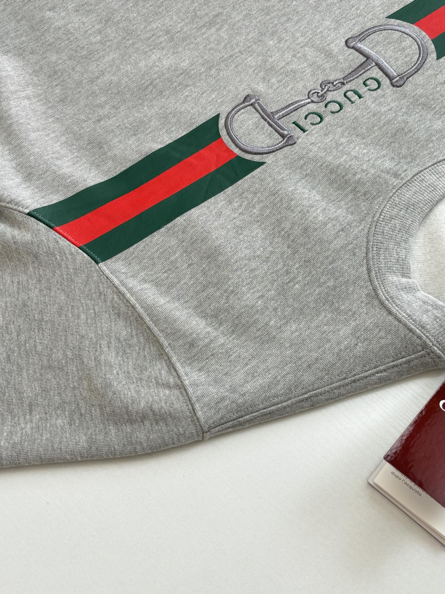 Light gray sweatshirt with green and red stripe graphic on sleeve and cuff