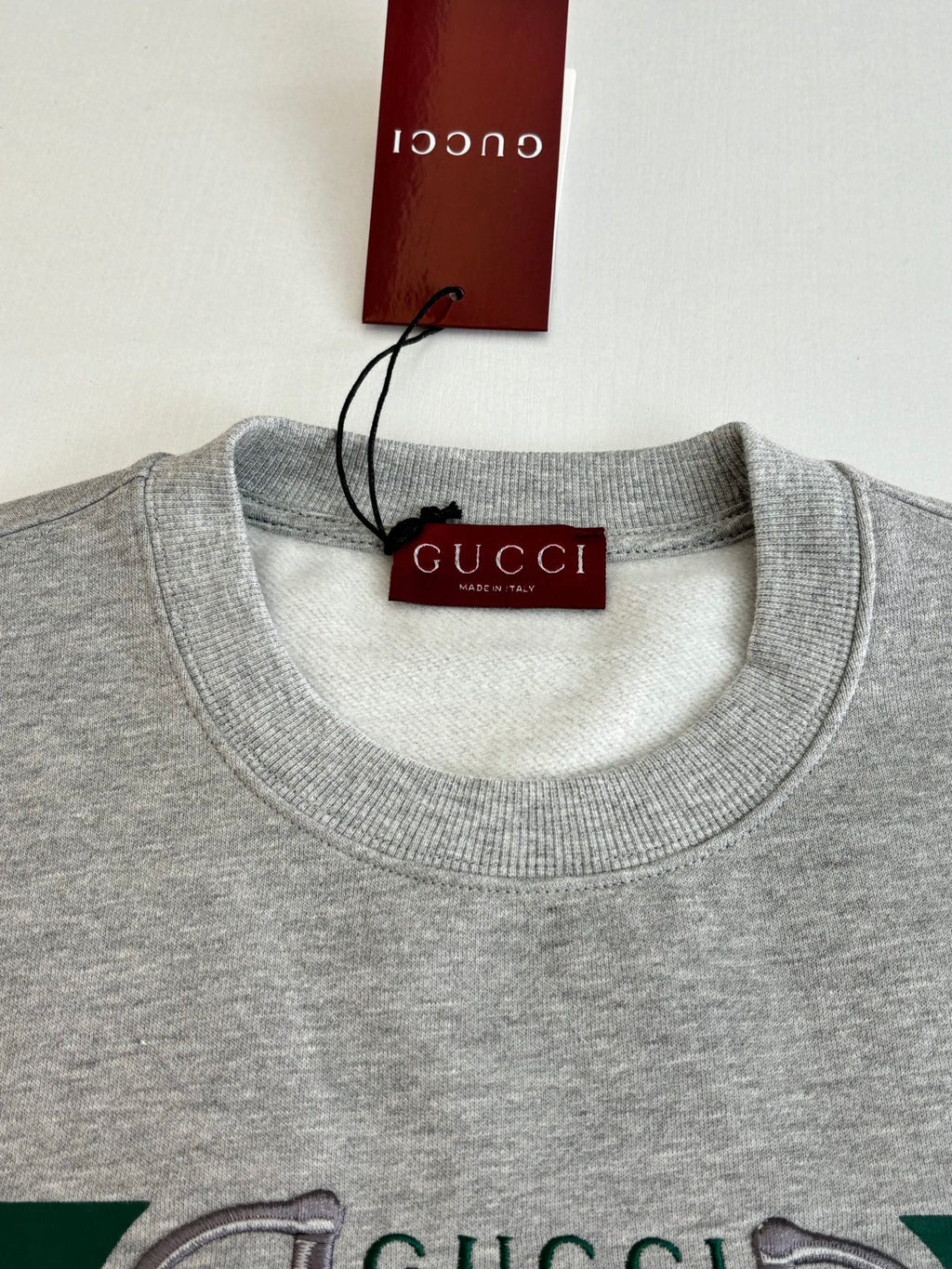 Light gray crew-neck sweatshirt close-up with hanging Gucci brand tag