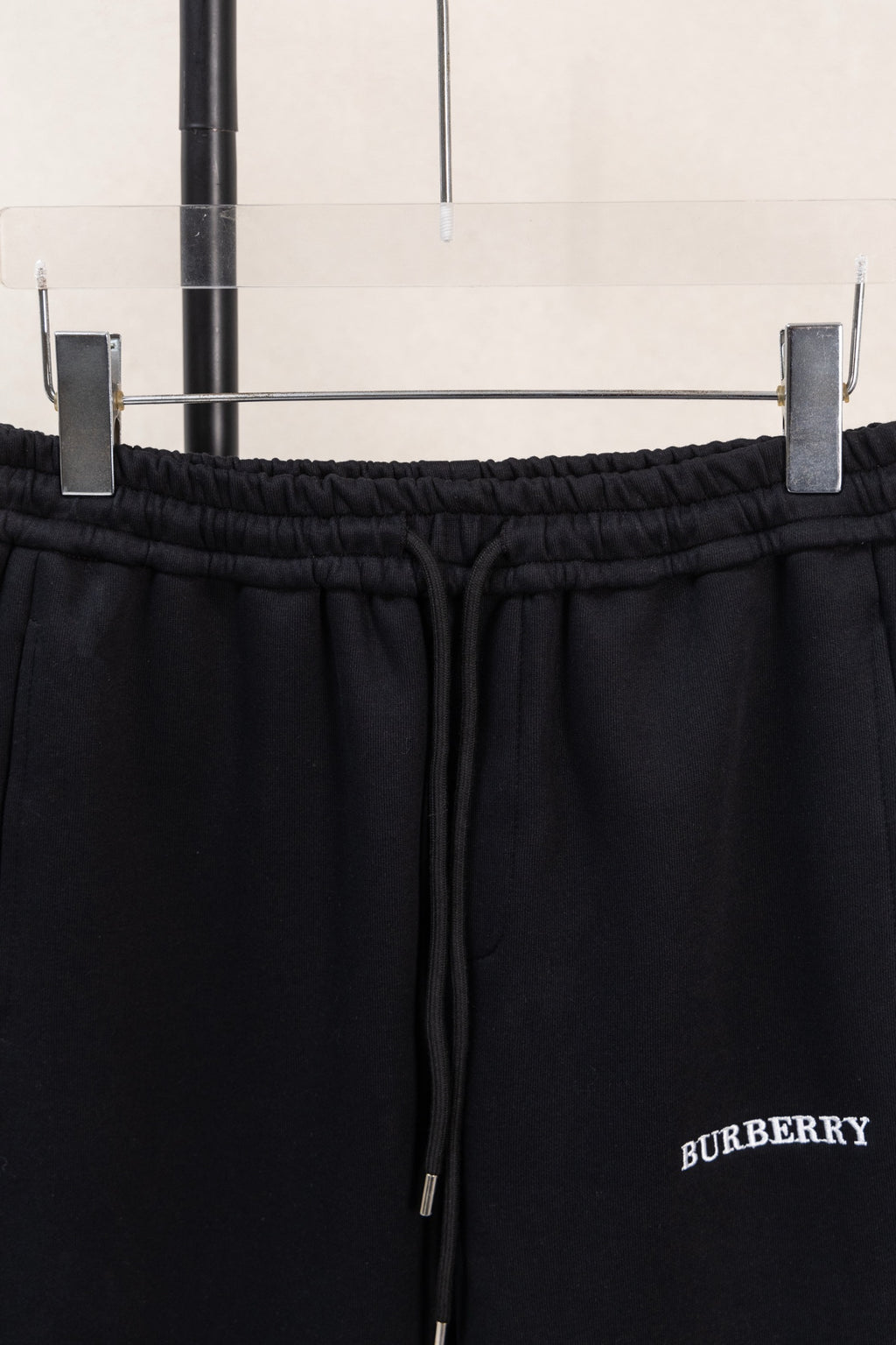 Black elastic waistband and drawstring close-up with side logo embroidery