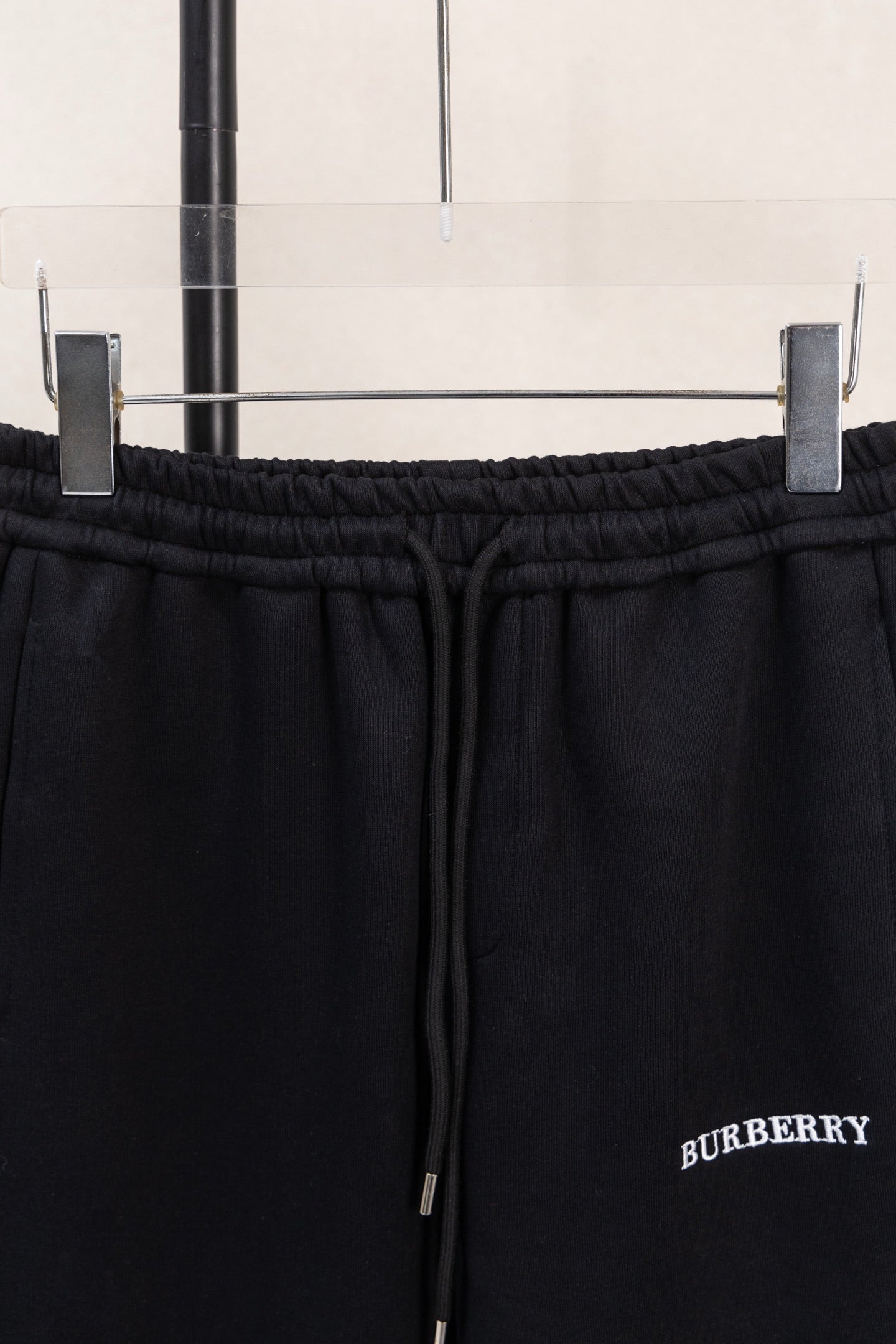 Black elastic waistband and drawstring close-up with side logo embroidery