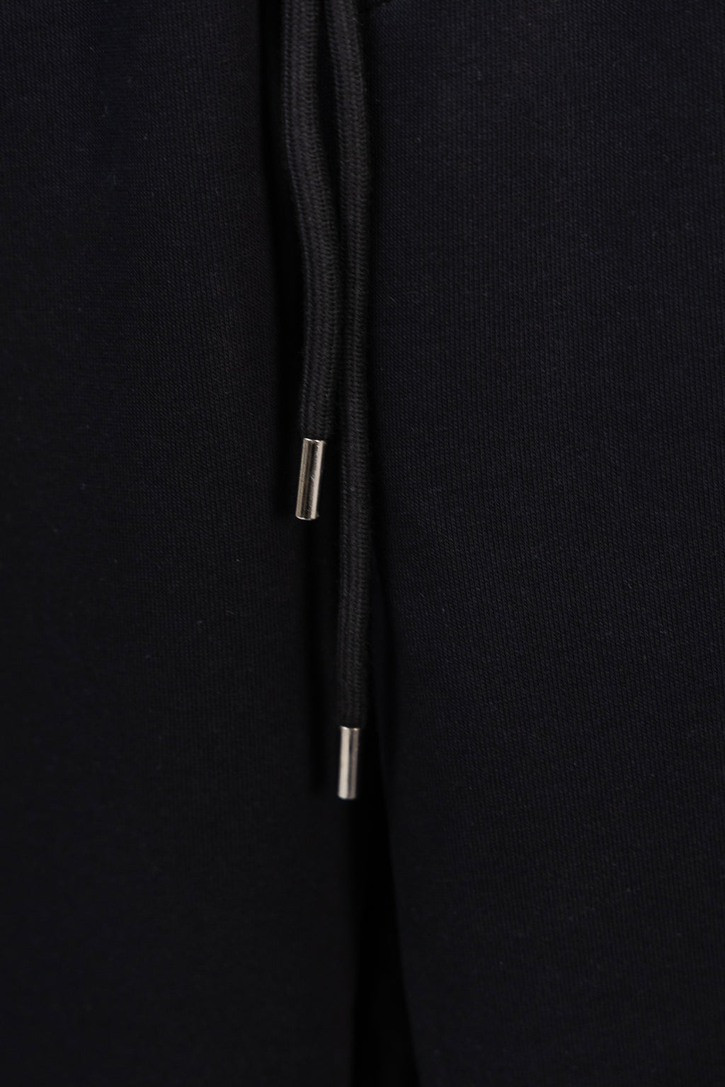Black drawstring with metal aglets at the end of the cord
