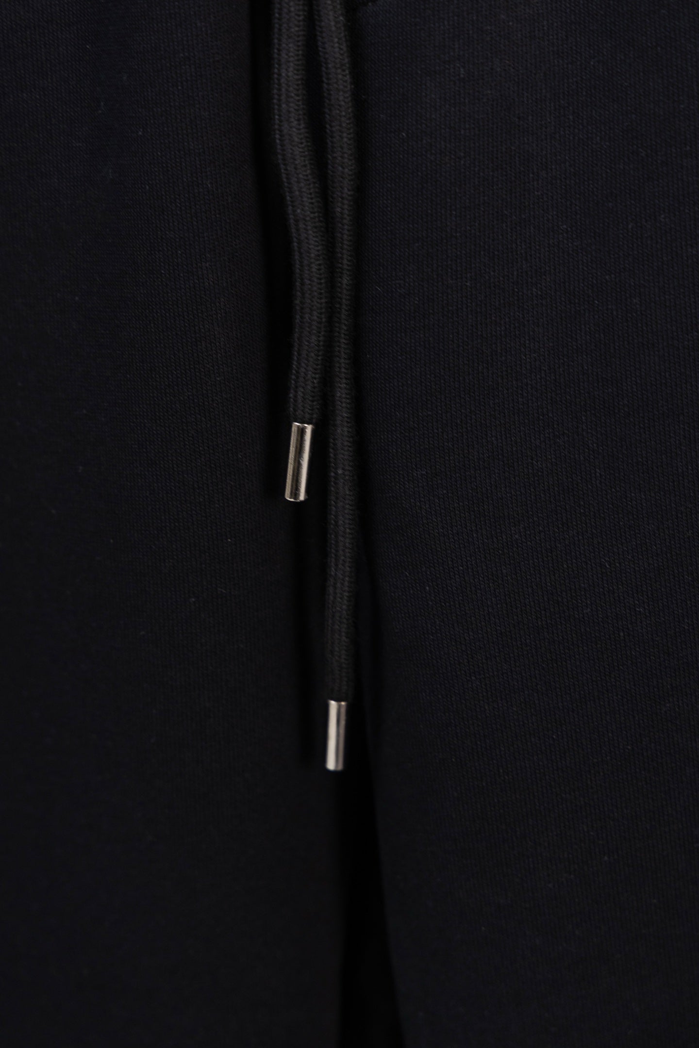 Black drawstring with metal aglets at the end of the cord