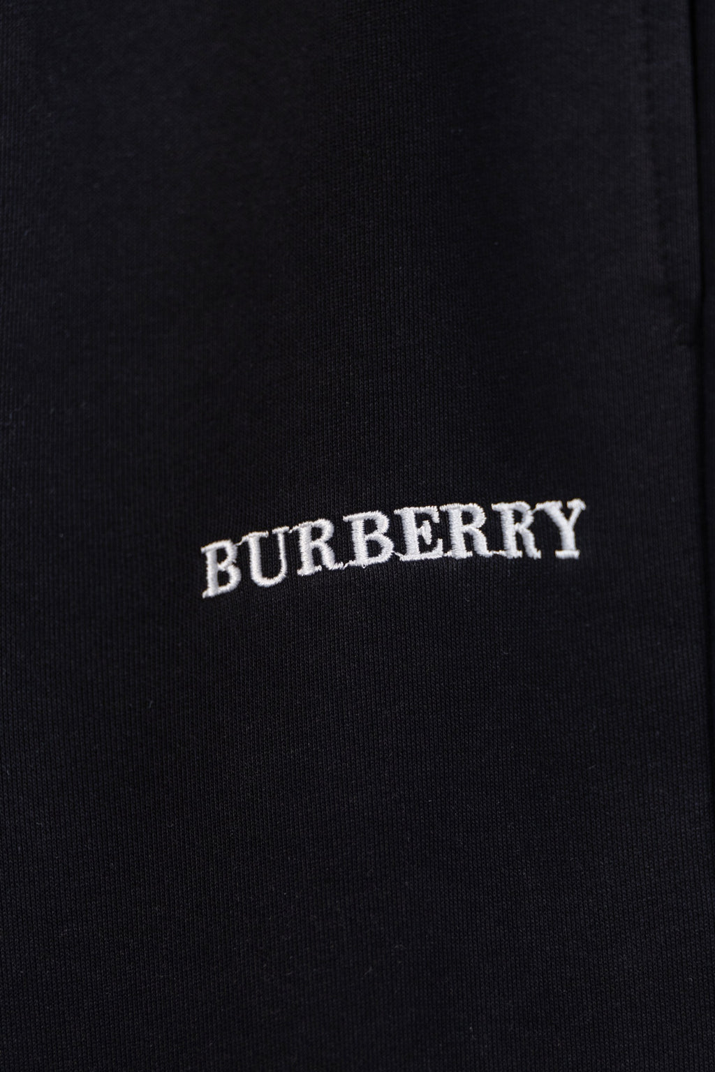 Black pants with embroidered BURBERRY logo text on the fabric
