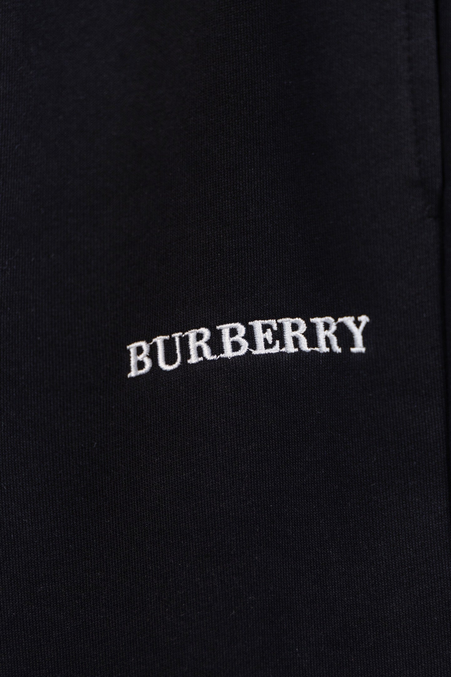 Black pants with embroidered BURBERRY logo text on the fabric
