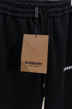 Black drawstring pants with hanging tan brand tag at the waistband