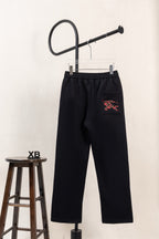 Black drawstring pants with colorful embroidered pocket emblem and straight legs