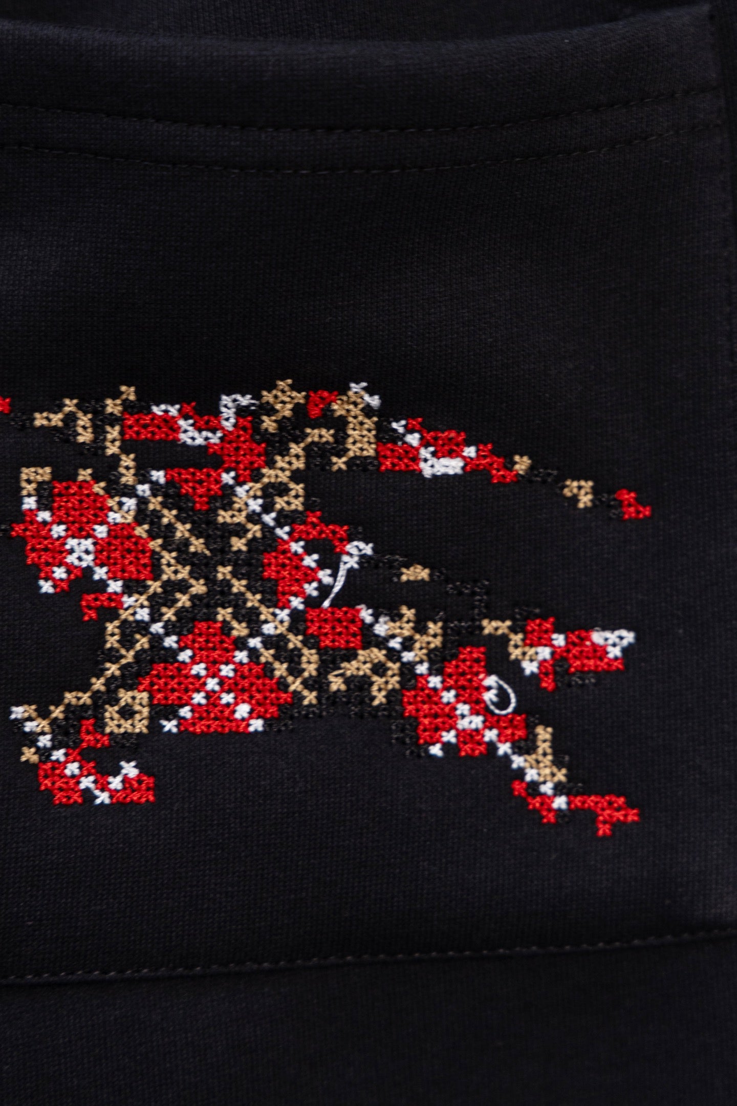 Black pants with large pixel-style red, gold, and beige embroidered emblem