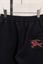Black drawstring pants with side pocket and red multicolor emblem