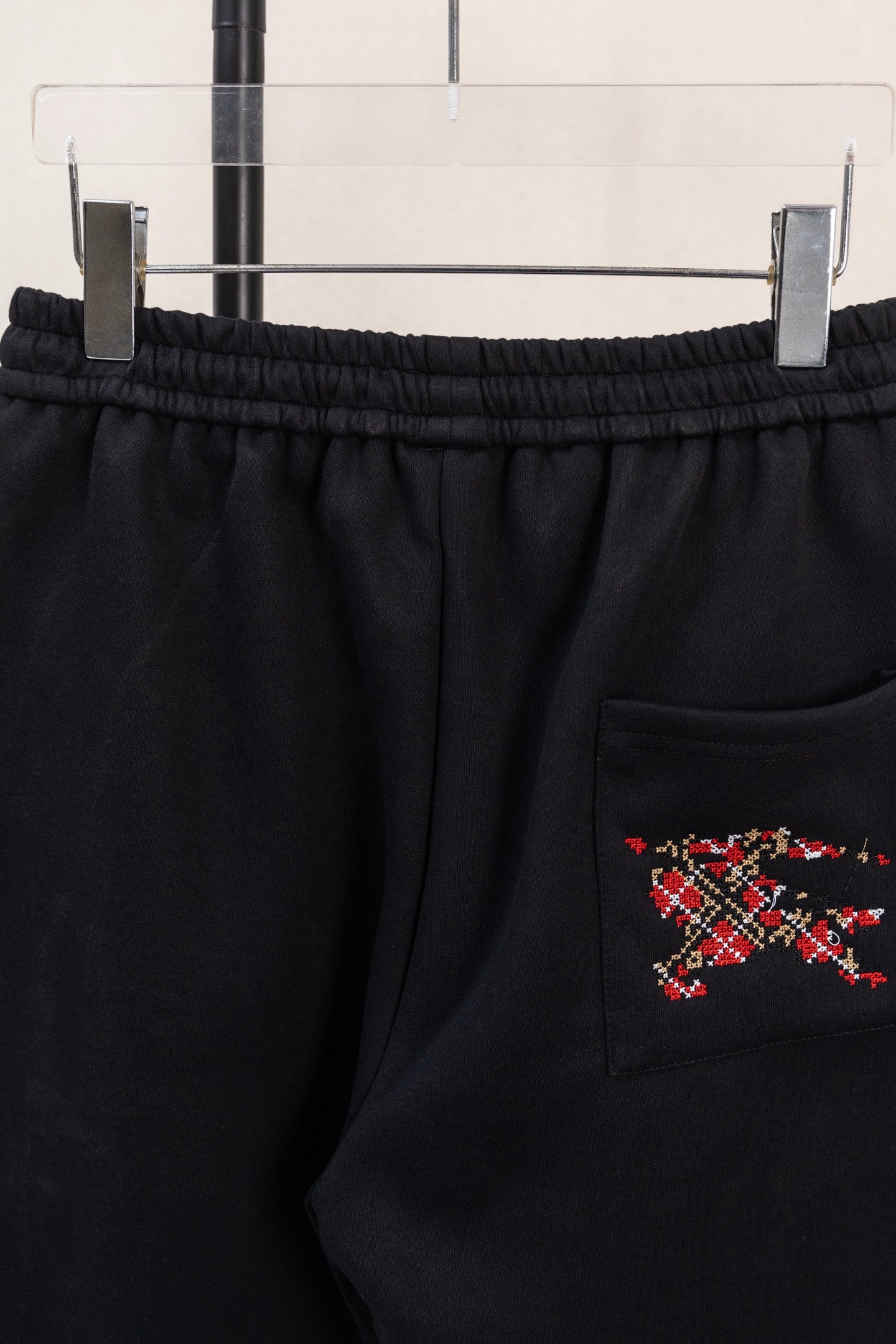 Black drawstring pants with side pocket and red multicolor emblem