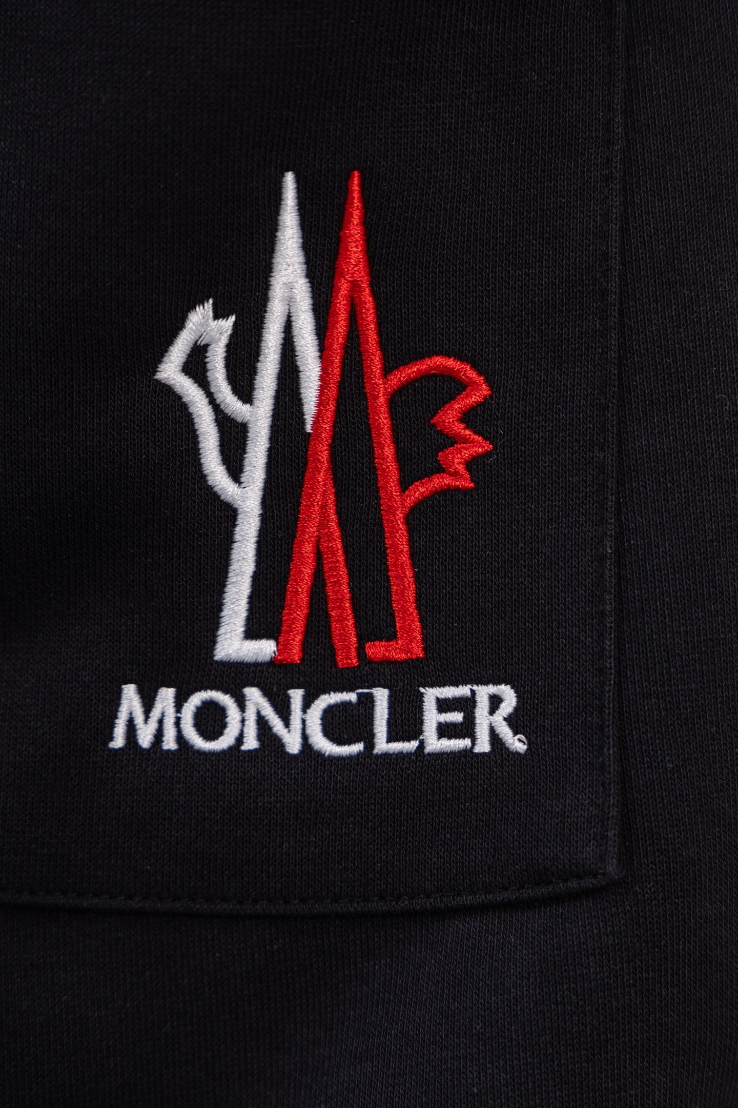 Moncler crest logo on black pants pocket, red and white