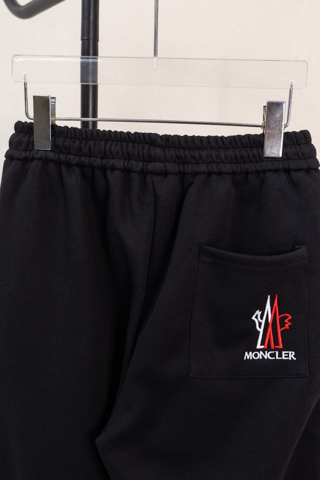 Black pants with elastic waistband, side pocket, and Moncler logo patch