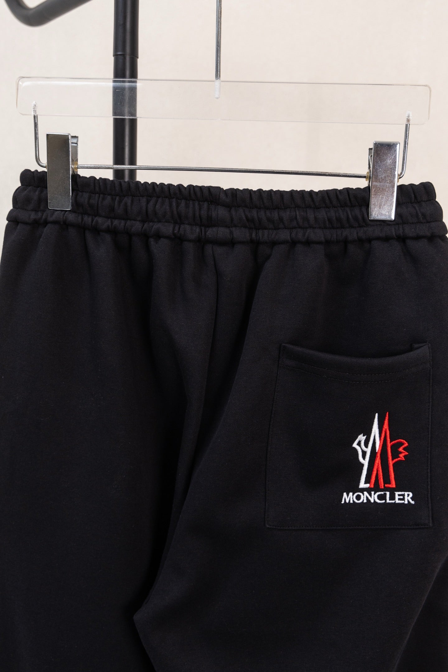 Black pants with elastic waistband, side pocket, and Moncler logo patch