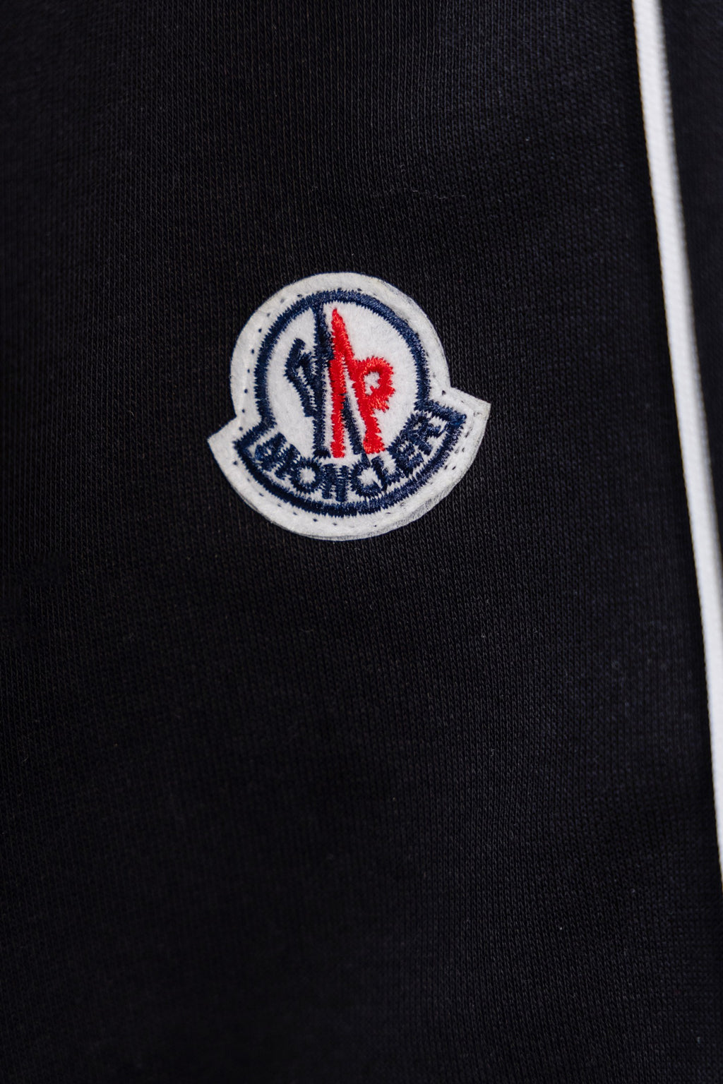 Moncler crest logo patch on black pants fabric