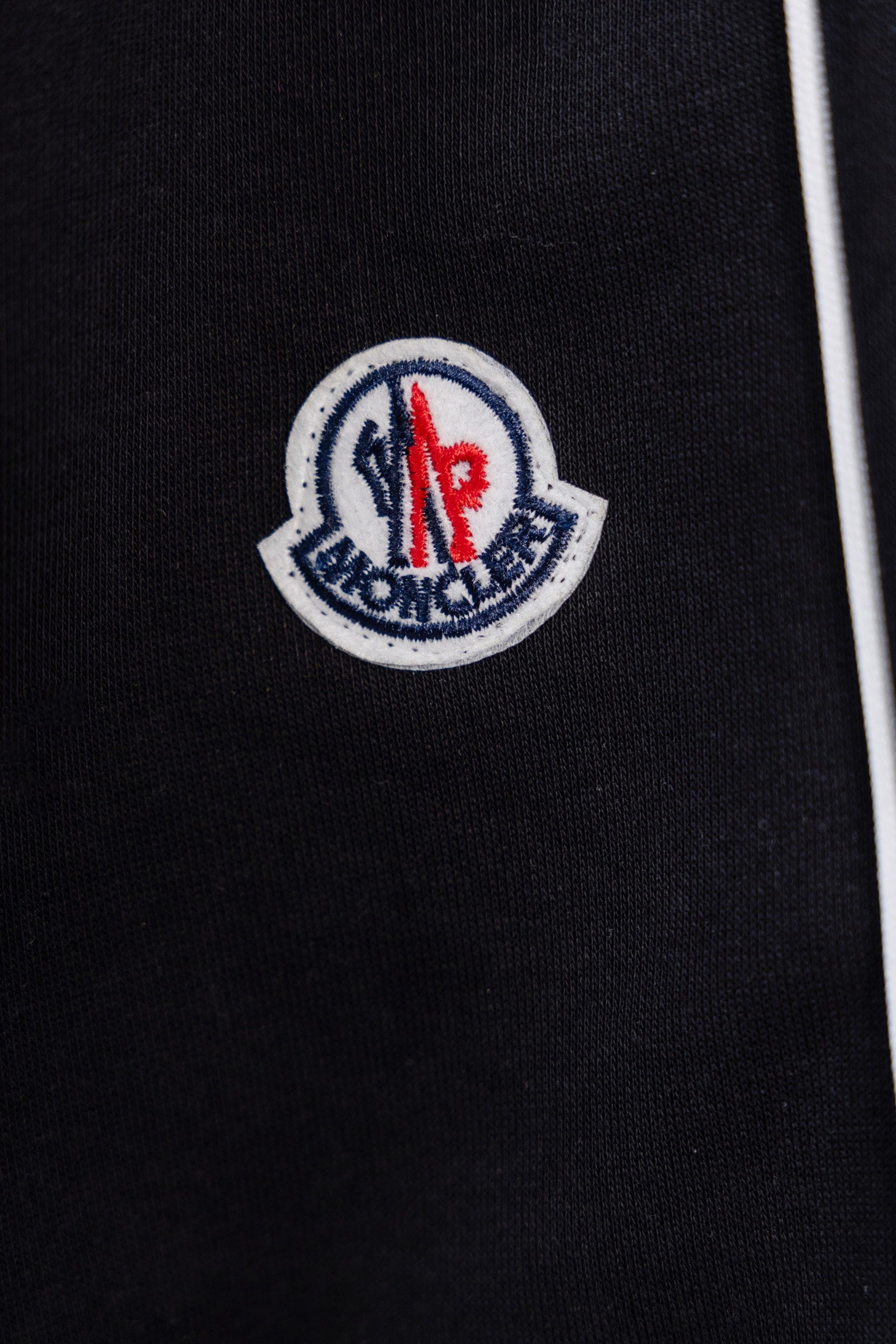 Moncler crest logo patch on black pants fabric