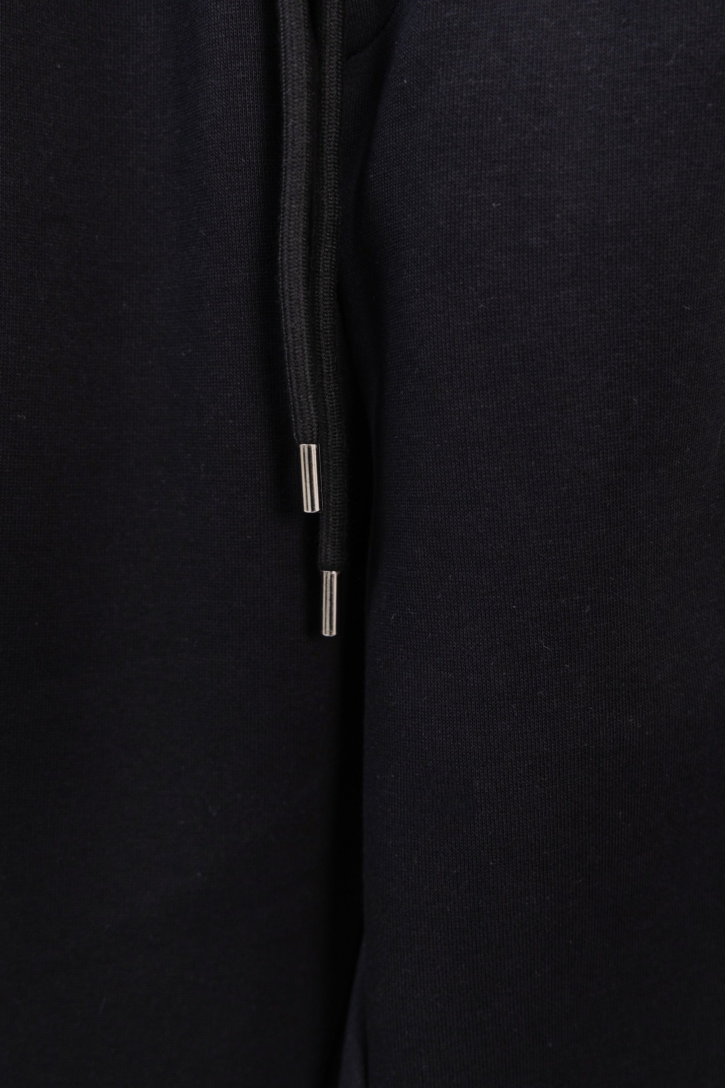 Black drawstring pants with metal-tipped cords and smooth fabric