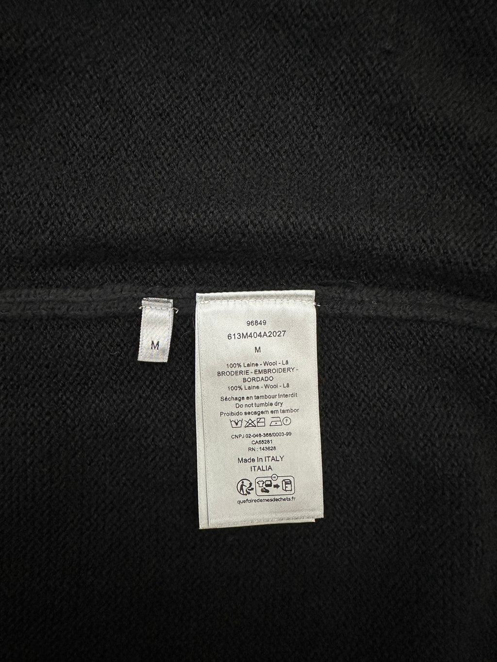 Dark knit jacket interior showing size and fabric care label, size M